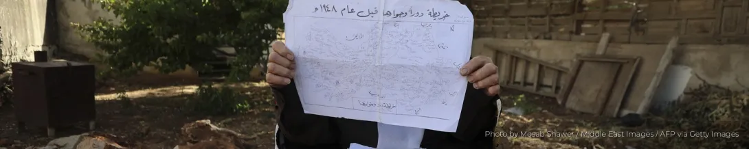 A Palestinian elder holds up a map of the Palestinian village of Dura and its environs before 1948.