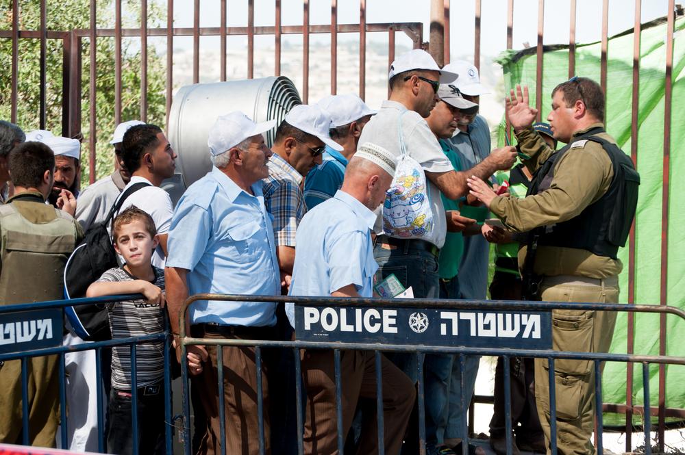 Israeli soldiers hold Palestinians at a crowded checkpoint in Bethlehem, blocking them from entry to Jerusalem.