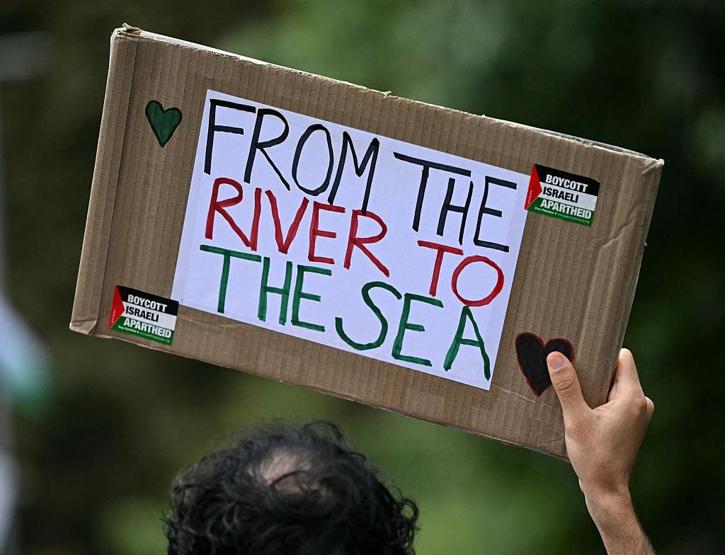 Sign that says "From the River to the Sea" with two small stickers of the Palestinian flag that say "Boycott Israeli Apartheid."