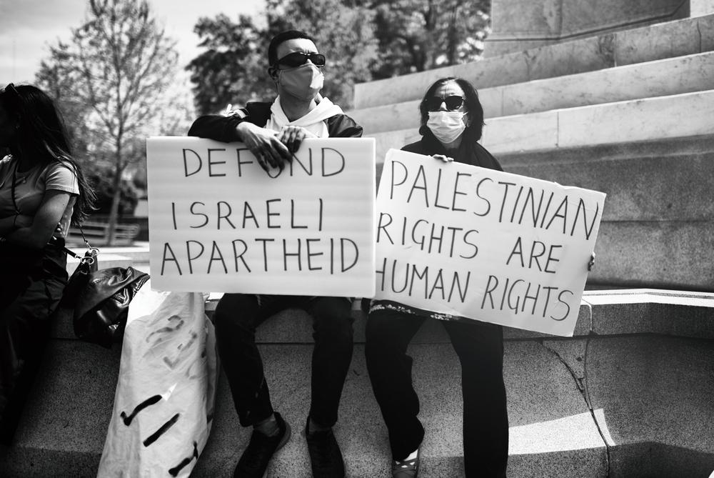 Protestors carry signs that say "Defund Israeli Apartheid" and "Palestinian Rights are Human Rights."