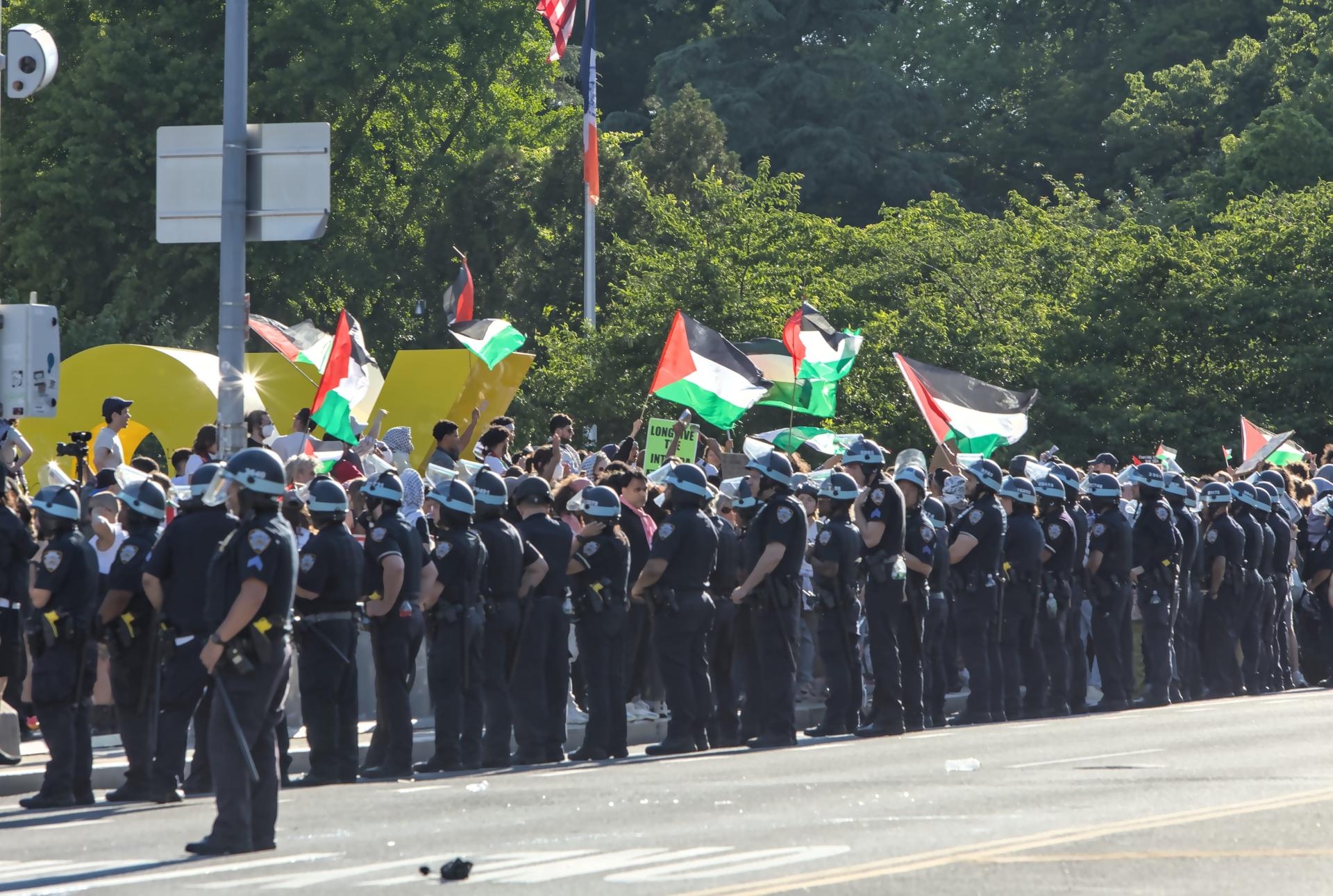 Large number of NYPD officers with batons and helmets watch a Gaza ceasefire protest in Brooklyn, NY.