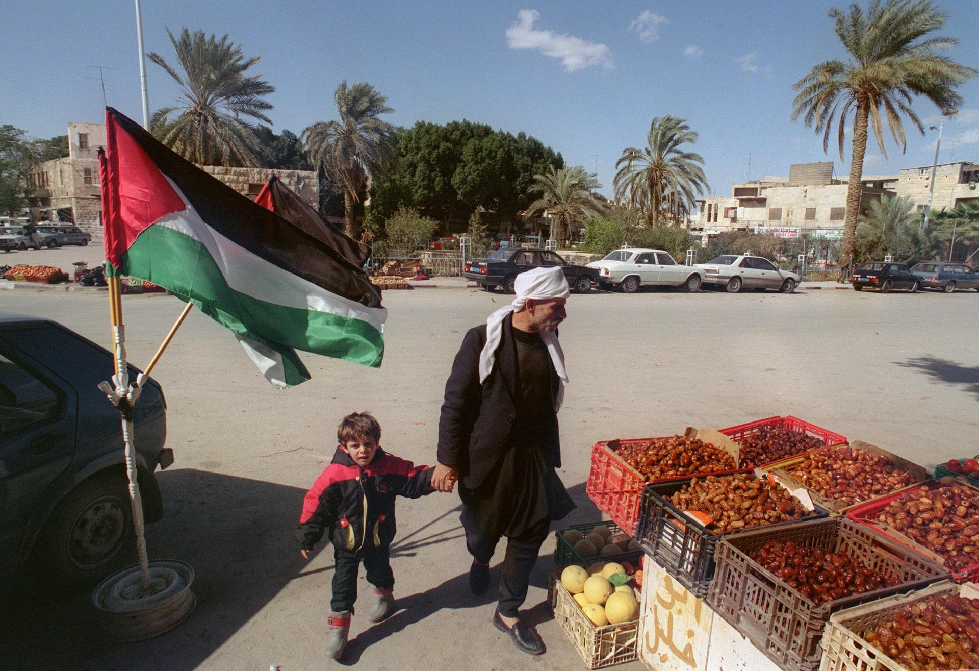 A Palestinian man and child walk in a market in Jericho, 1994.