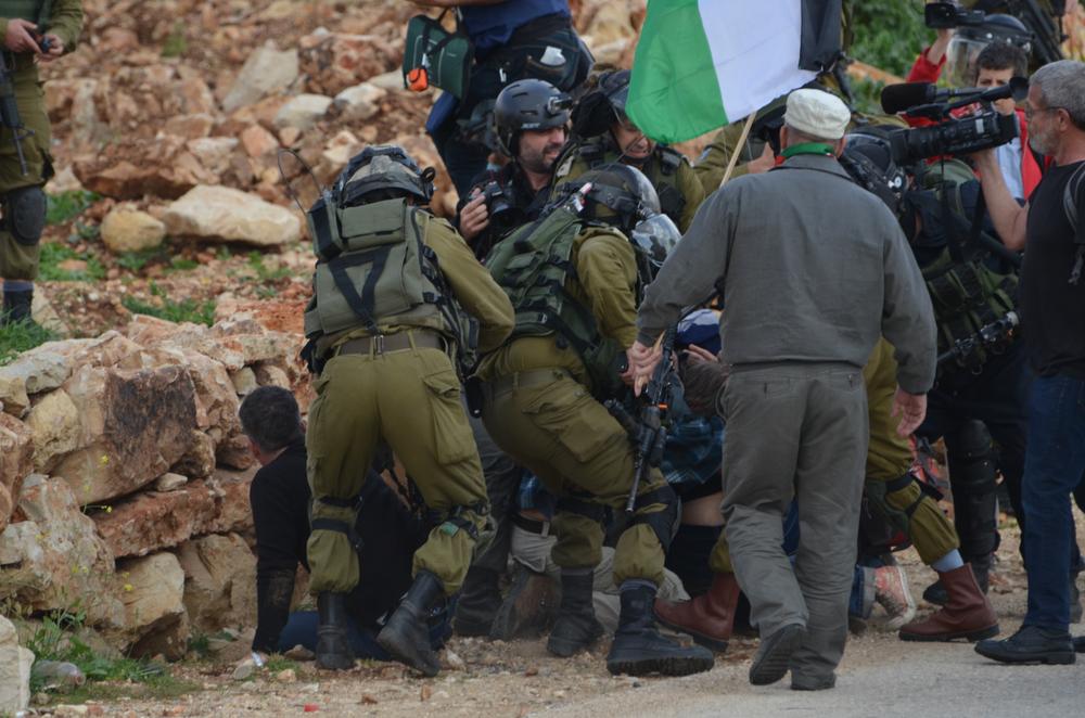 Israeli soldiers tackle protestors, forcing them to the ground, during a protest in the West Bank village of Nabi Salih as journalists capture video footage.