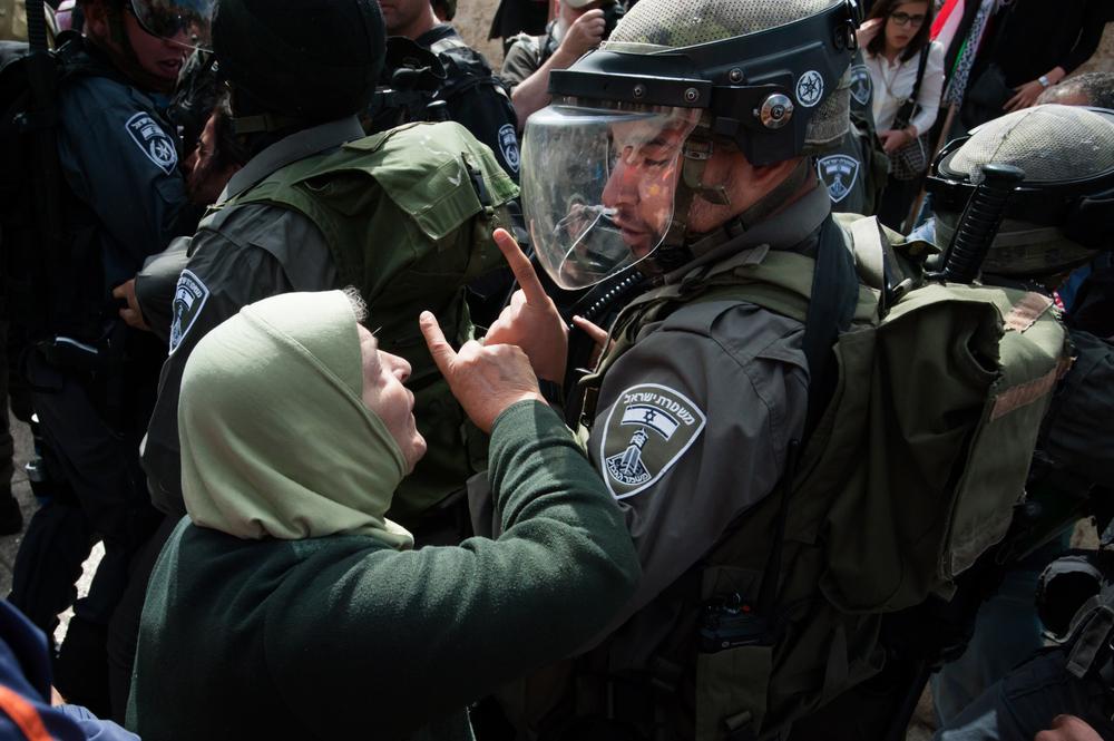 An elderly Palestinian woman confronts an Israeli soldier, with her pointer finger raised. In the background are several additional Israeli soldiers. Nakba Day protest at the Damascus Gate, occupied East Jerusalem. May 15, 2013.
