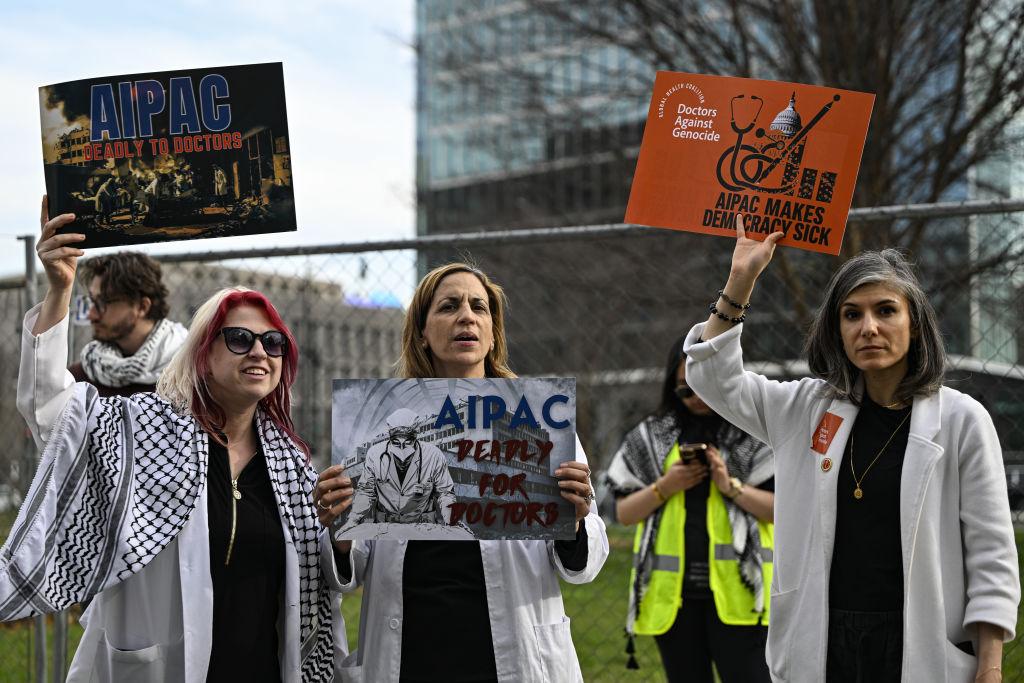 Doctors in white coats protest outside of the AIPAC headquarters in Washington DC. Signs say "AIPAC: Deadly to Doctors" and "Doctors Against Genocide: AIPAC Makes Democracy Sick."
