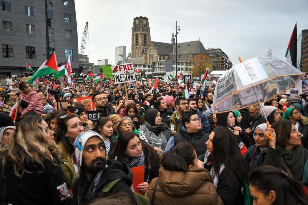 Large crowd, many wearing kuffiyehs, carrying signs, and waving Palestinian flags during a protest against Israel's war on Gaza in Rotterdam, Netherlands. November 19, 2023.