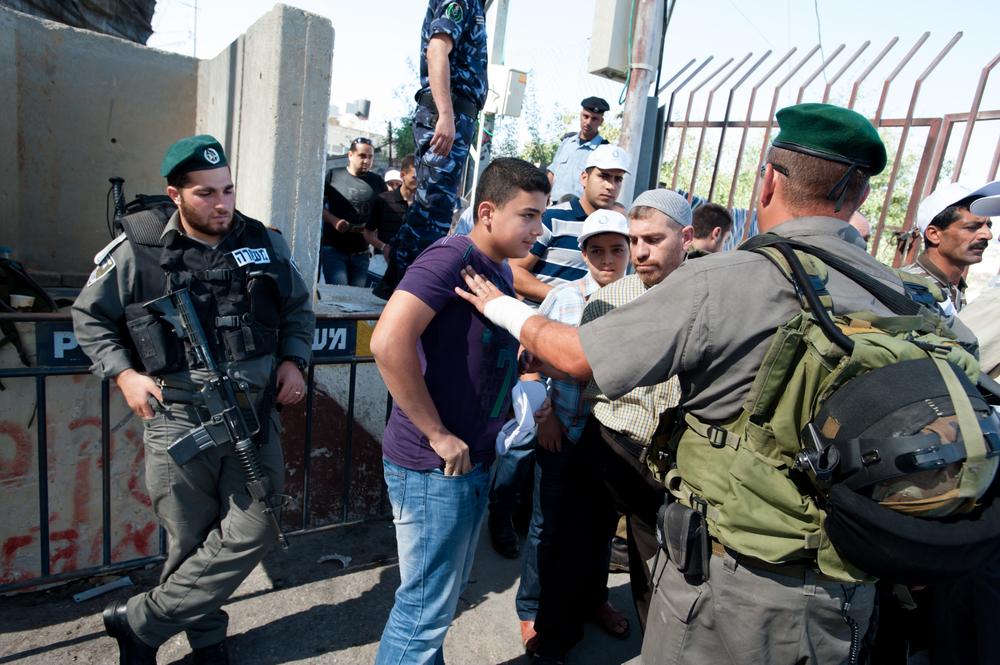 IDF soldiers block a young Palestinian from entering Jerusalem through a West Bank checkpoint to perform Friday prayers during the last Friday of Ramadan.