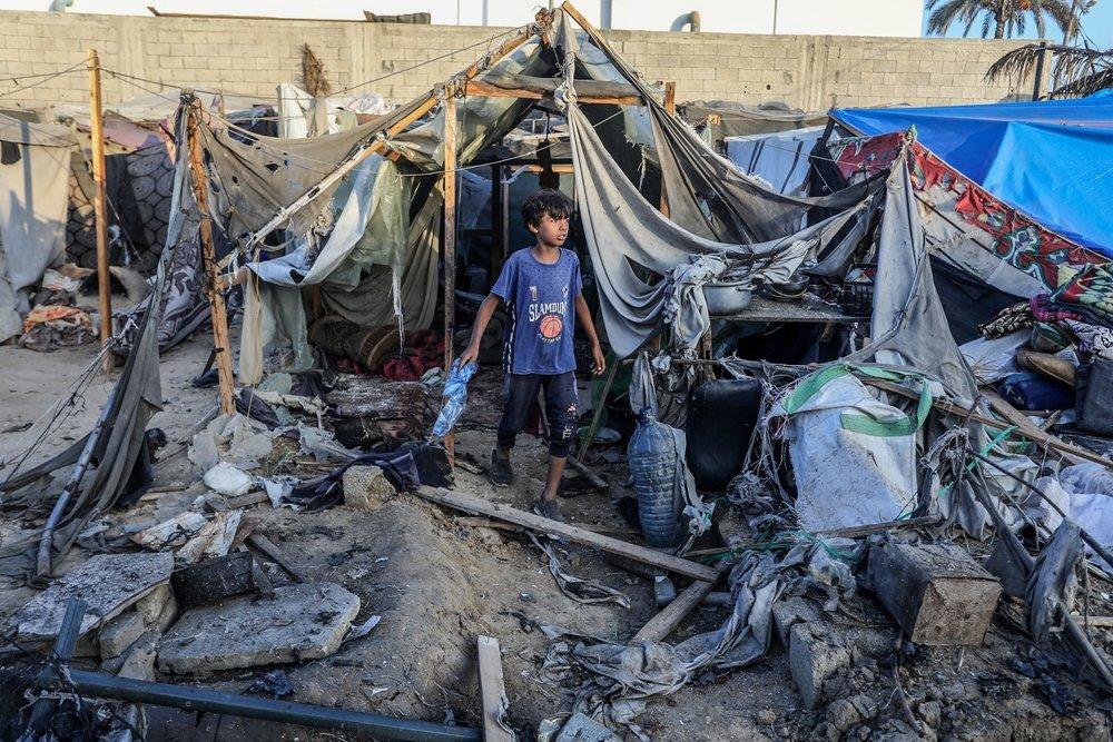 A Palestinian child walks between the ruins of tents bombed by Israel.