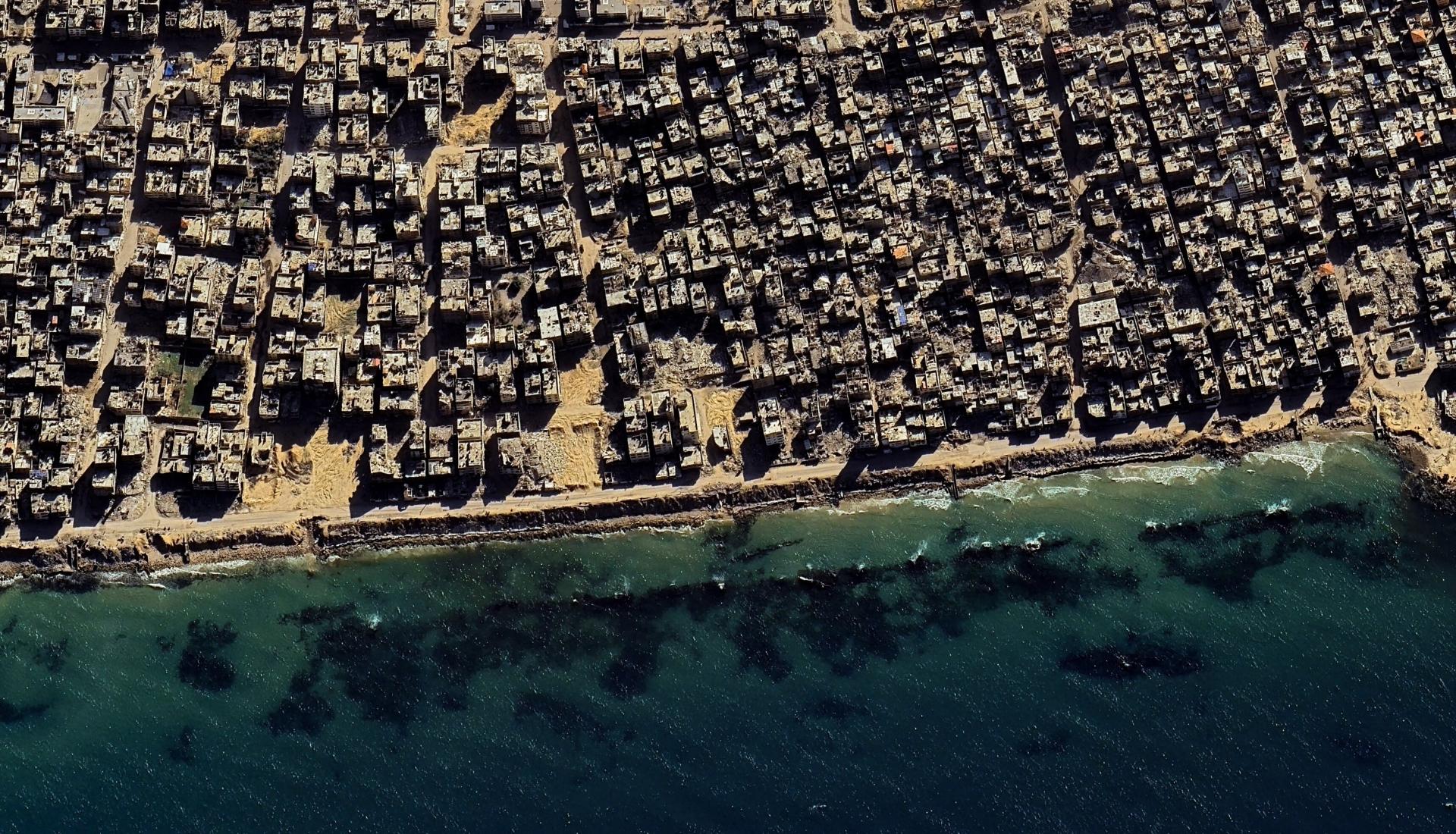 Aerial view of Gaza Strip destruction along the Mediterranean sea coastline, showing rubble, destroyed buildings, and destroyed roads.