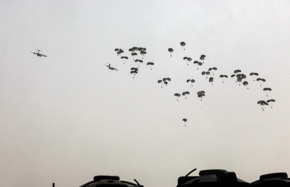 Ground-level view of an aid airdrop over Gaza, a method critiqued as ineffective and dangerous.