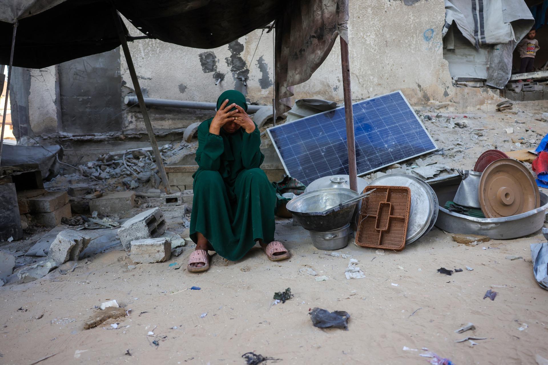 A woman sits with the kitchen cookware she was able to salvage from her destroyed home in Khan Yunis due to an Israeli airstrike on October 29, 2025, after the ceasefire agreement was in effect.