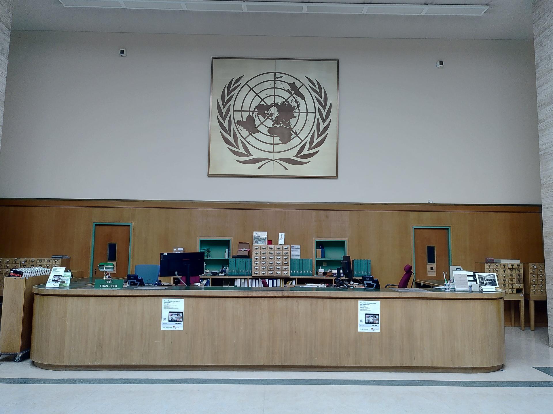 View of the UN library in Geneva's information desk with the UN logo overhead.
