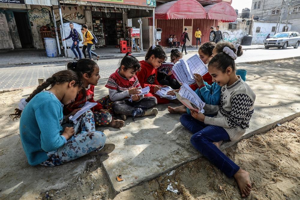 In an image from 2021, Palestinian schoolchildren read their books outside in Gaza.