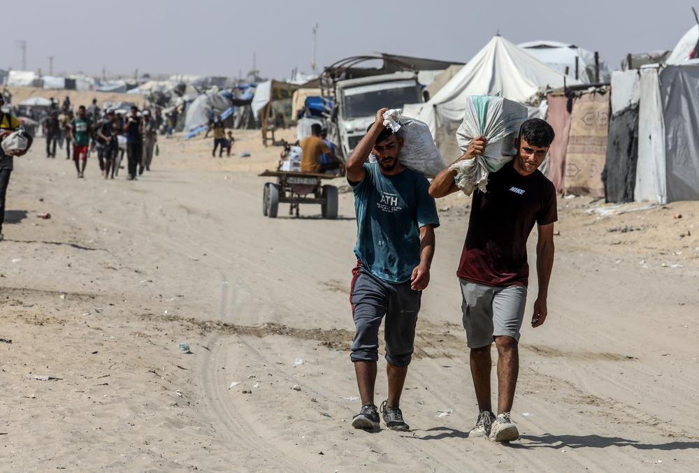 Palestinians walk to and from a GHF distribution site to collect aid.
