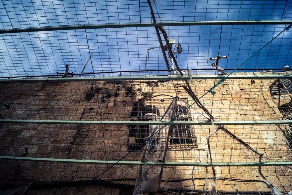 Metal netting and surveillance cameras sit overhead of a street in Hebron, in the occupied West Bank.
