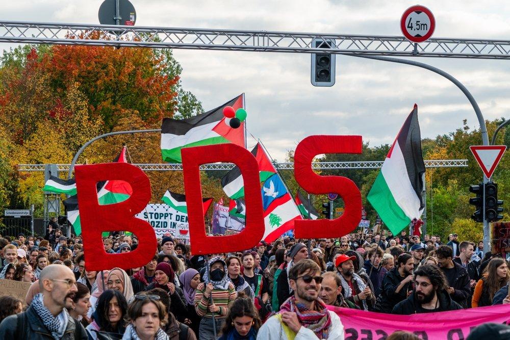 At a large Palestine solidarity protest in Germany against Israel's war on Gaza, protestors carry Palestinian flags and the letters BDS.