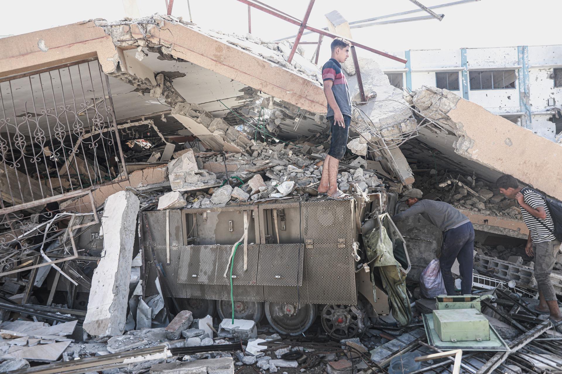 Palestinians in Gaza City's Tel al-Hawa neighborhood inspect rubble and ruins of a building in Gaza which has collapsed over Israeli military vehicles and ammunition left behind following the Gaza ceasefire. October 11, 2025.