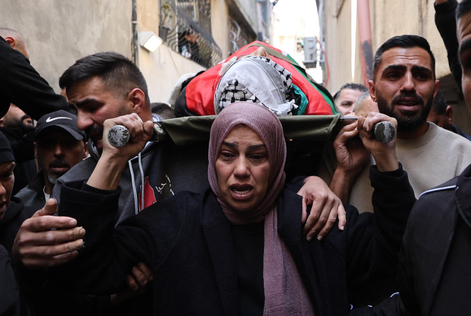 A Palestinian mother leads the funeral procession for her 15 year old son who was killed by the Israeli military during a raid on the Dhisheh refugee camp in the West Bank near the city of Bethlehem. She is surrounded by other mourners in the funeral procession.