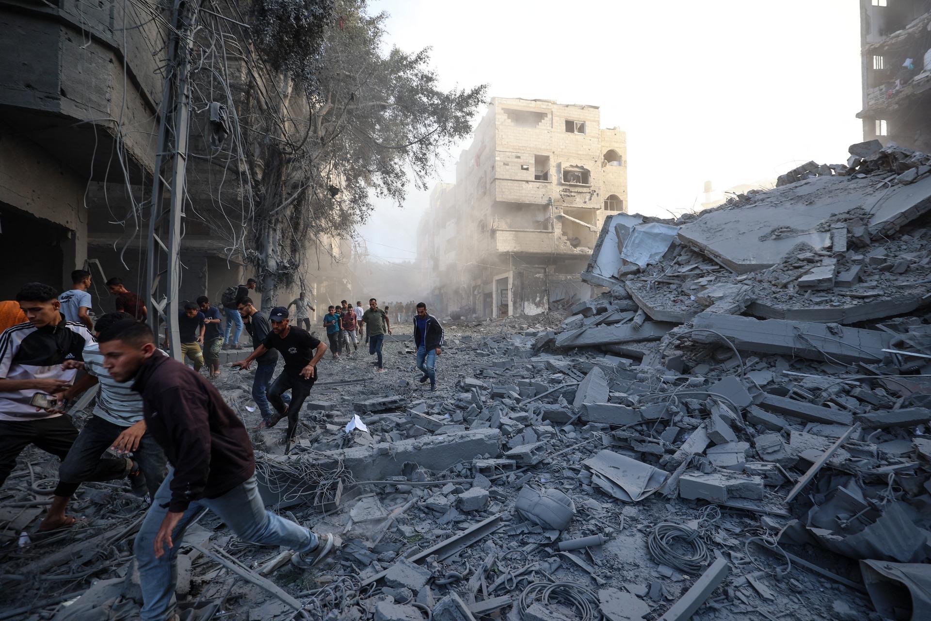 Palestinians flee as Israel bombs a building in the central Gaza Strip's Bureij refugee camp only days after the US-brokered ceasefire agreement. October 19, 2025.