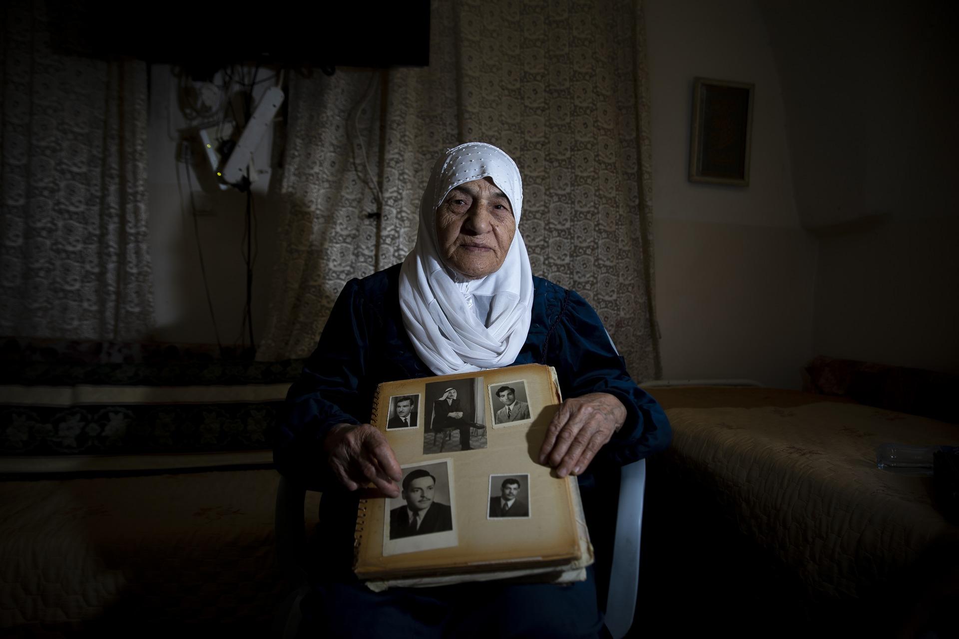 A survivor of the Deir Yassin Massacre, Meryem Aqil Umm Usame holds an image of family members killed in the Zionist paramilitary massacre of the Jerusalem-area village as part of the ethnic cleansing of Palestine, or Nakba.