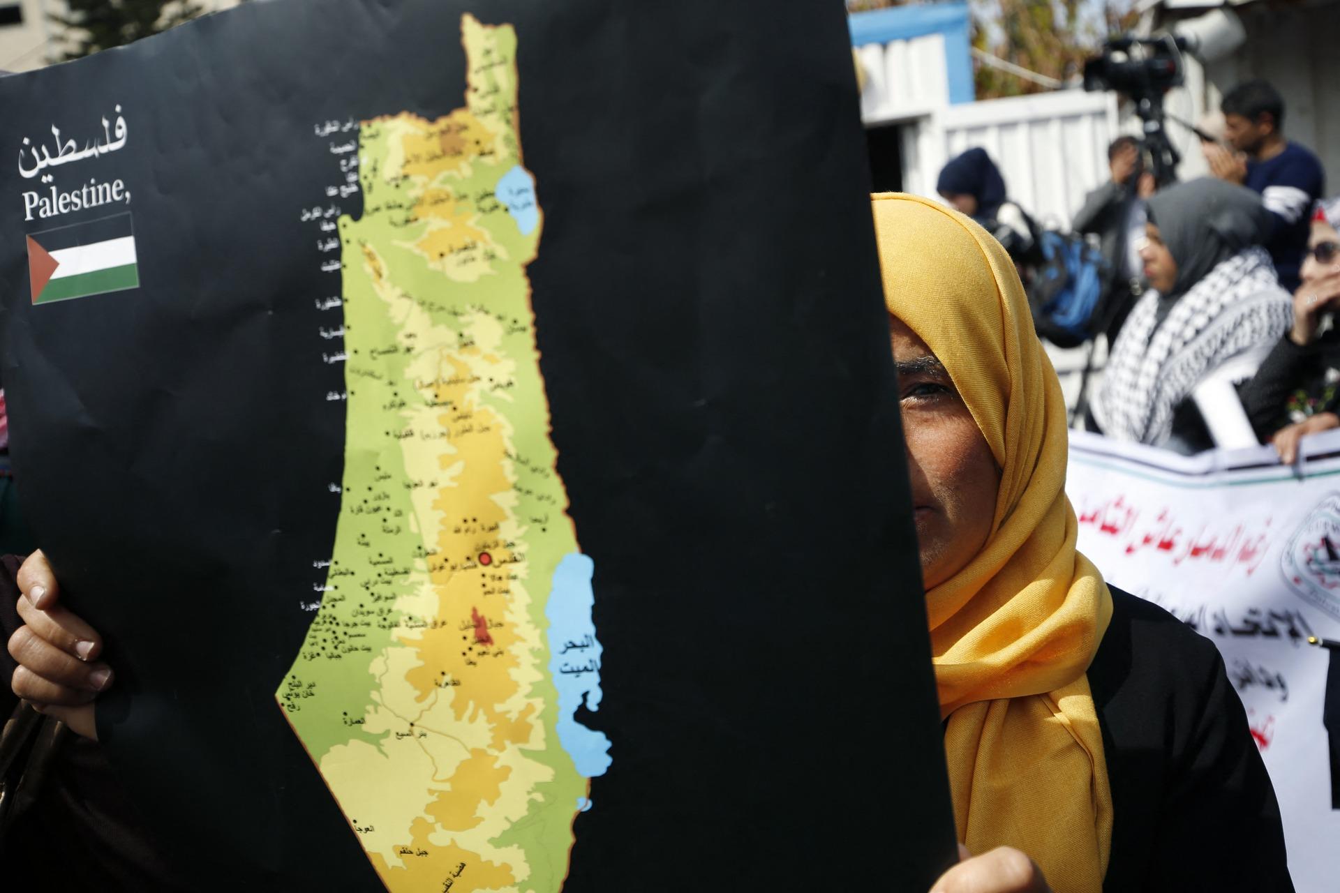 A Palestinian woman carries a map of historic Palestine at a rally against Trump's "deal of the century" in Gaza City on February 27, 2020.