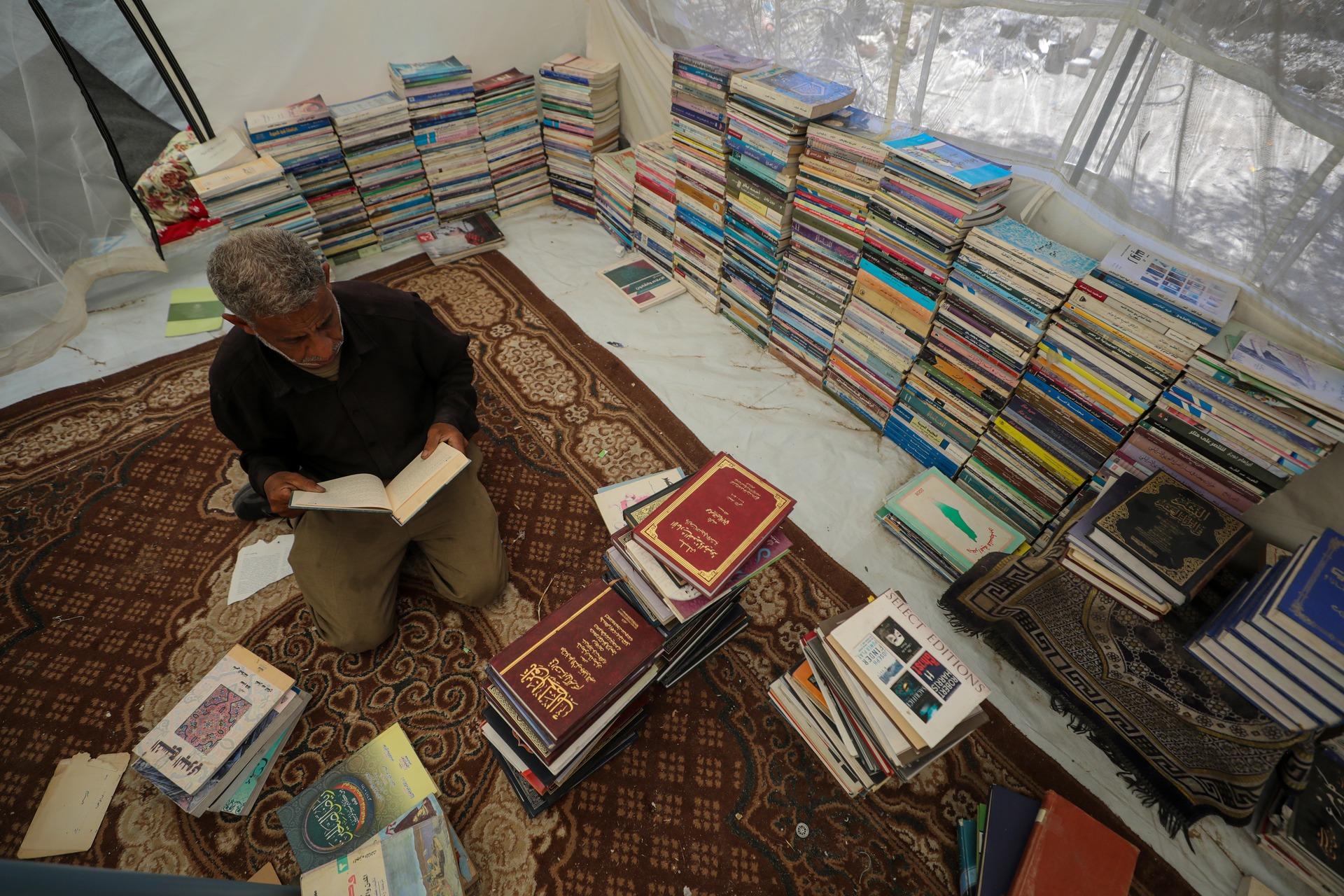 A Palestinian bookseller organizes his collection for sale in Deir al-Balah in the central Gaza Strip, where he lives in displacement. HIs surviving books were recovered under the rubble of his destroyed home in Beit Lahia.