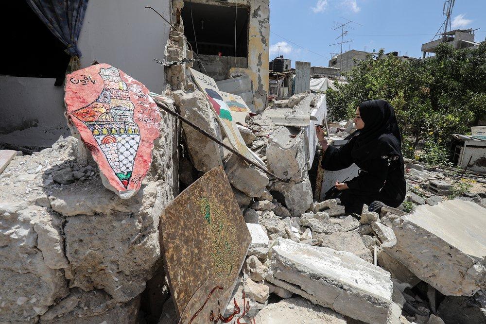 A Palestinian artists paints Palestinian symbols on the ruins of her home after Israel's May 2021 war on Gaza.