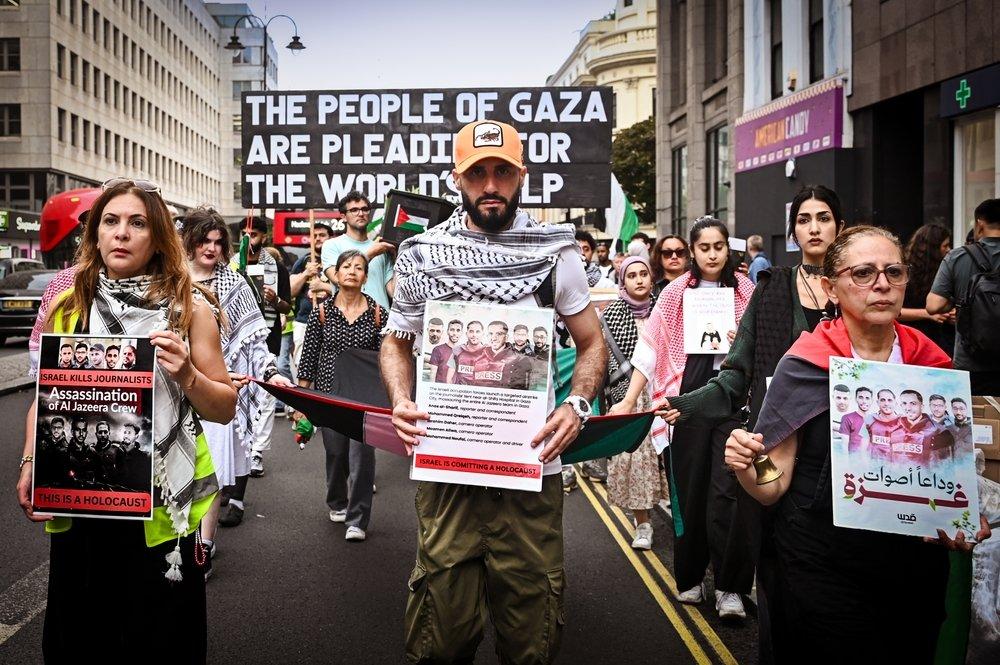 Protestors in London carry signs honoring journalists in Gaza assassinated by Israel.