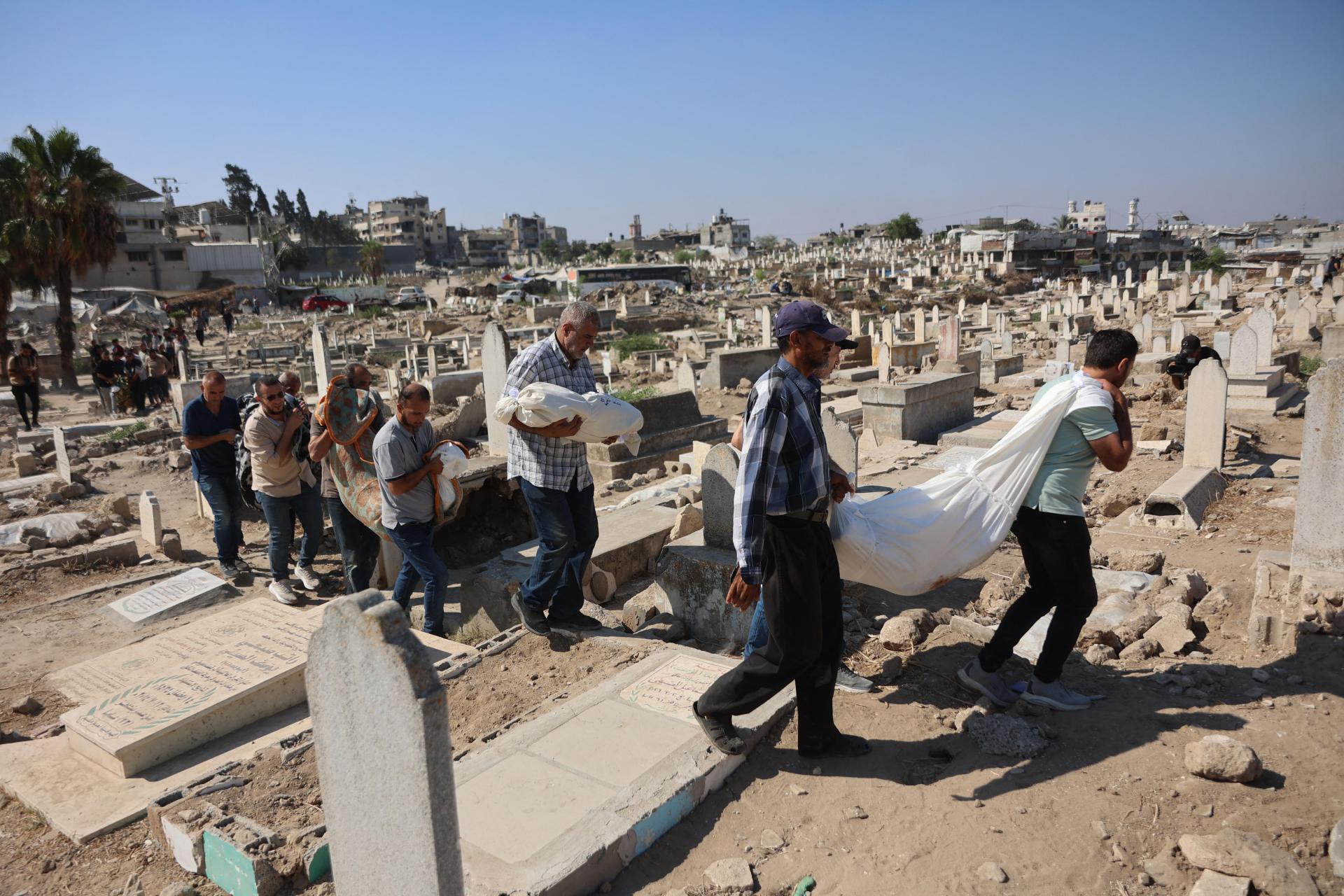 Mourners in a Gaza cemetary prepare to bury victims killed in Israel's July 21, 2026 airstrike on a residential building in Gaza City's Sabra neighborhood.