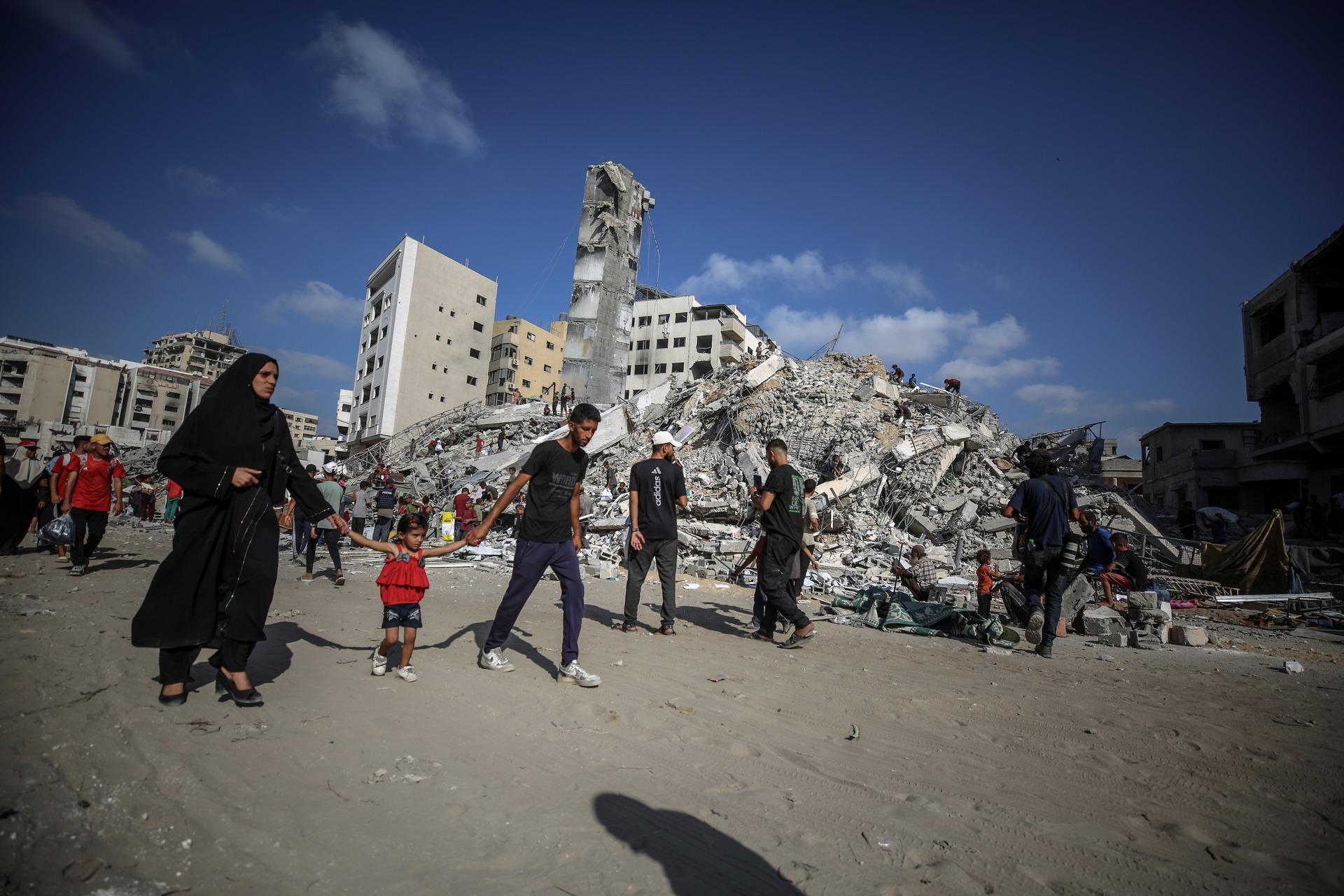 A Palestinian family walks near the rubble of Al-Sousi Tower near the Rimal neighborhood in Gaza City after an Israeli airstrike on September 6, 2025.