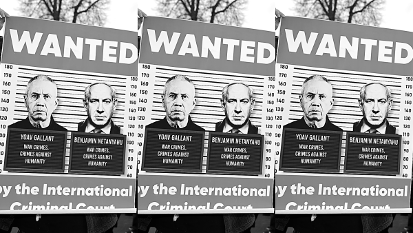 Protest sign has mock-mugshot photos of Israeli Defense Minister Yoav Gallant and Prime Minister Benjamin Netanyahu that say "WAR CRIMES, CRIMES AGAINST HUMANITY." Surrounding the mugshot graphic is large text that reads "WANTED BY THE INTERNATIONAL CRIMINAL COURT."
