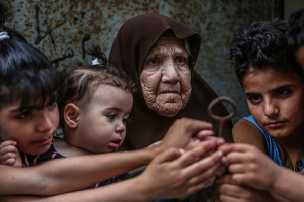A Palestinian Nakba survivor carries the key to her home from which she was expelled in the 1948 Nakba along with her grandchildren.