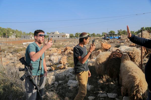 Armed Israeli settlers harass a Palestinian on his land in the West Bank.