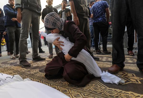 A Palestinian woman cradles her infant who was murdered in an Israeli airstrike in the earliest days of its genocide in Gaza.
