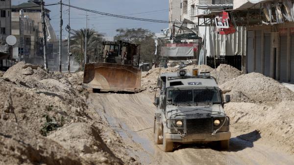 Israeli military vehicles, one a weaponized buildozer, drive through a destroyed road of the Nur Shams Refugee Camp in the West Bank city of Tulkarm as part of Operation Iron Walls on February 26, 2025.