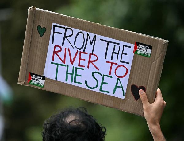 Sign that says "From the River to the Sea" with two small stickers of the Palestinian flag that say "Boycott Israeli Apartheid."