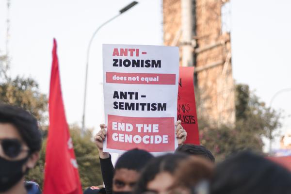 A protestor holds up a sign that says "ANTI-ZIONISM does not equal ANTI-SEMITISM, END THE GENOCIDE."