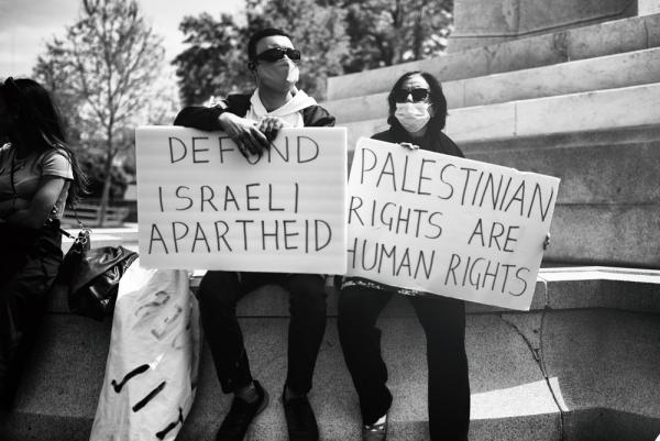 Protestors carry signs that say "Defund Israeli Apartheid" and "Palestinian Rights are Human Rights."