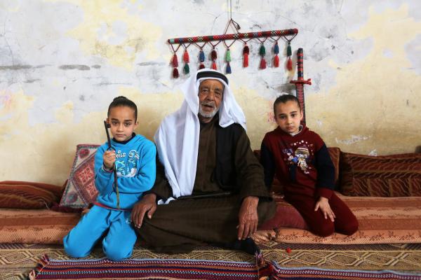 A Palestinian Nakba survivor and refugee in the Gaza Strip sits with his young granddaughters, one carries the key to her grandfather's home from which he was expelled in the 1948 Nakba.