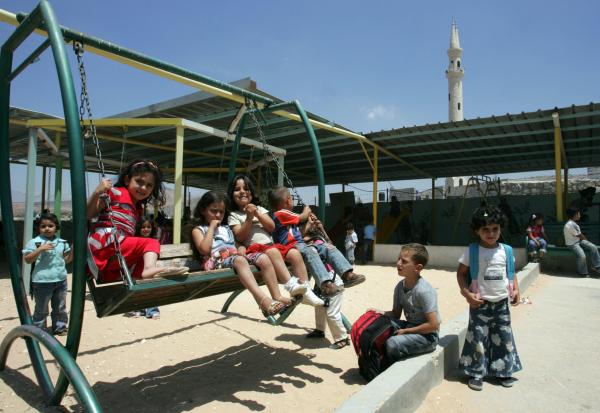 Palestinian children stand and others sit on a swing on the grounds of the Aqaba kindergarten, which as of this 2008 photo, was under demolition orders from the Israel.