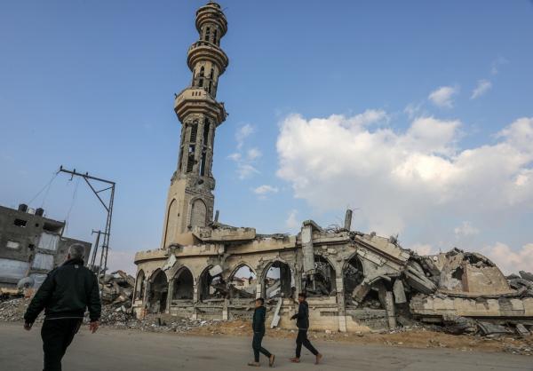 Palestinians walk past destroyed mosque and other buildings in Khan Yunis. January 2025.