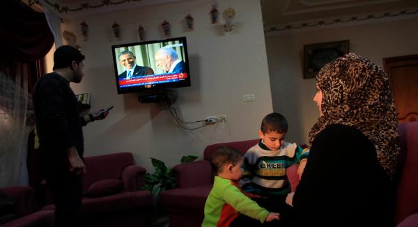 A Palestinian family watches coverage of US President Barack Obama's press conference with Israeli President Shimon Peres in 2013.