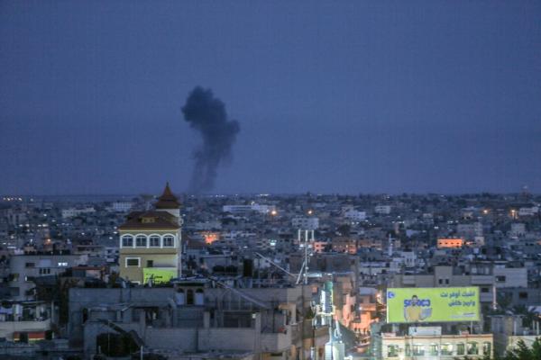 Smoke rises in the air over buildings after an Israeli airstrike in the Gaza Strip. Occuring in the early days of Israel's genocidal war on Gaza, these crowded residential and commerical areas were flattened by Israeli bombs.