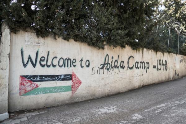 Graffiti on a wall in Bethlehem says "Welcome to Aida Camp" next to a Palestinian flag.