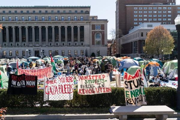 Palestine solidarity encampment protesting Israel's genocide in Gaza, image shows tents at Columbia University. Signs read "End the Siege on Gaza Now," "While You Read, Gaza Bleeds," and "ADMITTED STUDENTS: ENROLL IN REVOLUTION."