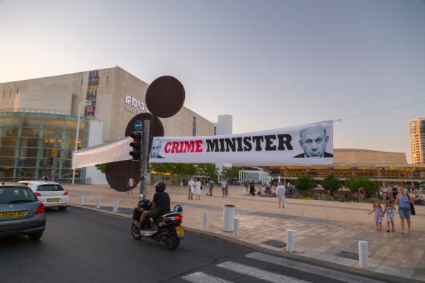 A banner in Tel Aviv with Netanyahu's image reads "CRIME MINISTER" in English. 2018.
