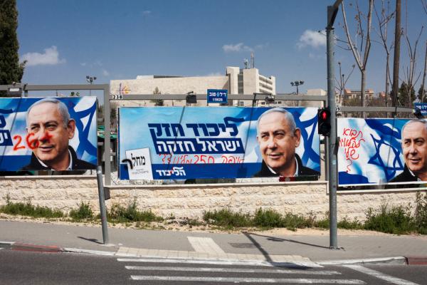 Likud banners with Netanyahu's photo and protest graffiti line a street in Jerusalem.
