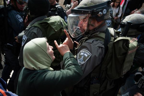 An elderly Palestinian woman confronts an Israeli soldier, with her pointer finger raised. In the background are several additional Israeli soldiers. Nakba Day protest at the Damascus Gate, occupied East Jerusalem. May 15, 2013.