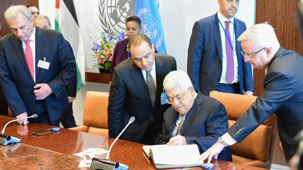 Palestinian Authority (PA) President Mahmoud Abbas signs the UN Secretary General's book, appearing with UN and PA officials, including Husam Zumlot, at UN headquarters. February 19, 2018.