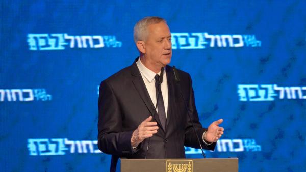 Benny Gantz speaks at a campaign rally event for the Blue and White Party, wtih party logos in the backdrop. Tel Aviv, 2019.